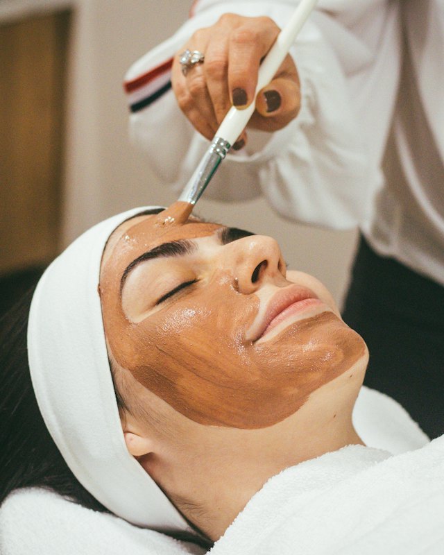 Profissional aplicando máscara facial em cliente